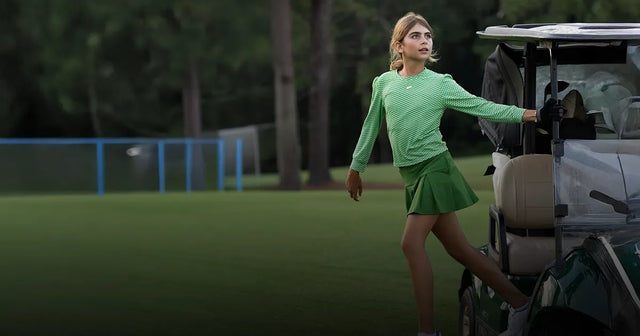 Bella Simoes in a golf cart on the course, wearing an outfit by Marie Birdie.