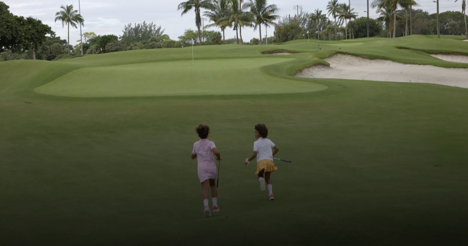 Two girls running in a golf course and dressed with stylish golf clothes by Marie Birdie.